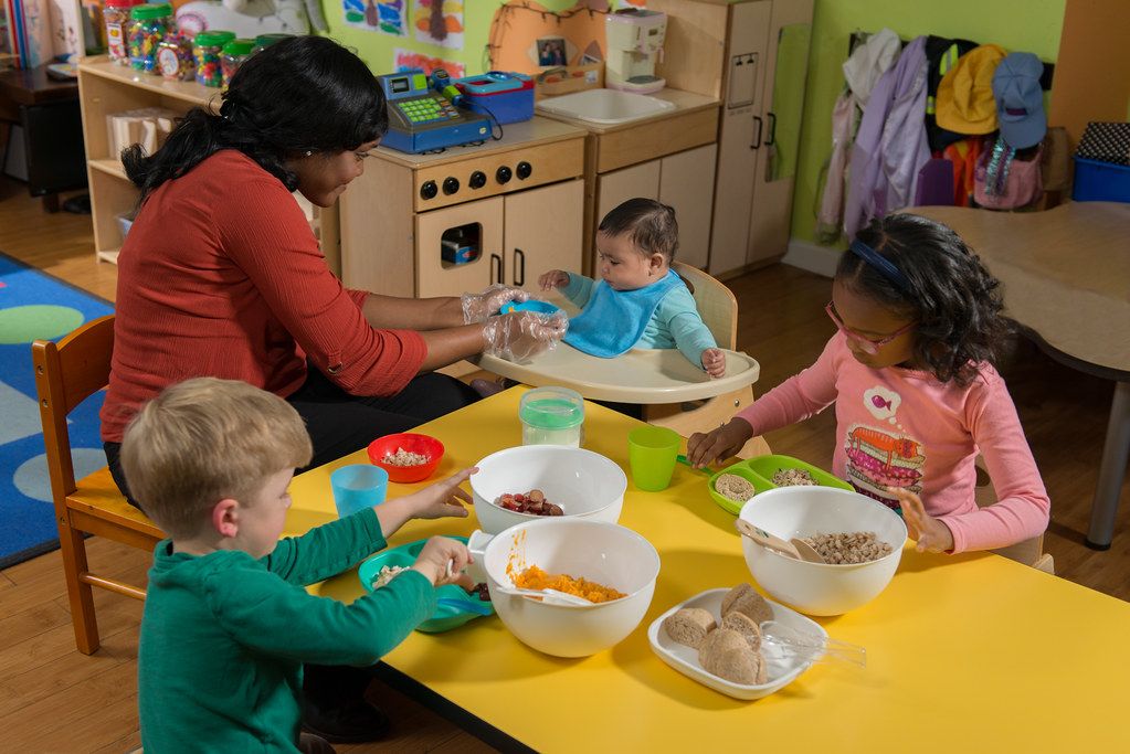 A teacher and preschool children sharing a family-style meal at a child care center