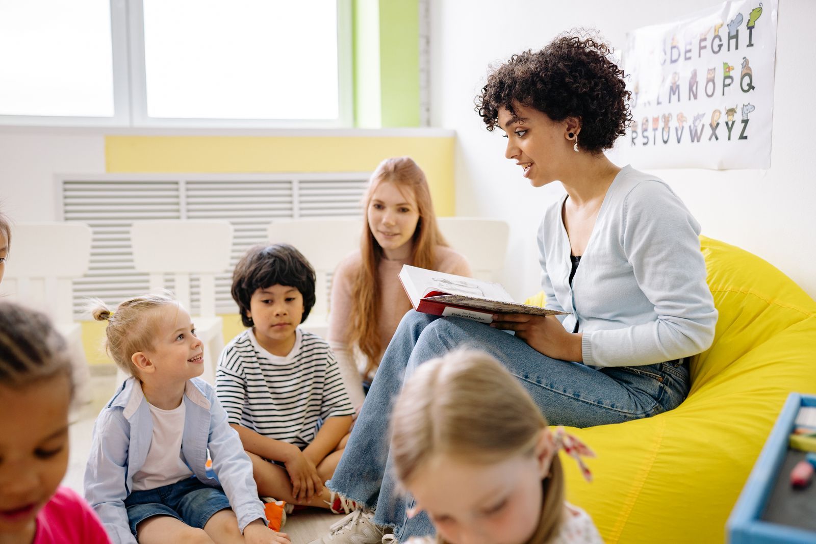 A teacher reading a picture book to a small group of preschool children