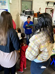 A teacher reading to children in a classroom while parents look on